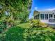 Side yard view from the exterior featuring manicured garden beds, a patio, and lush green grass at 17037 Se 76Th Creekside Cir, The Villages, FL 32162