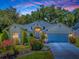 Charming single-story home illuminated at dusk, featuring a well-maintained lawn, lush landscaping, and attached two-car garage at 17037 Se 76Th Creekside Cir, The Villages, FL 32162