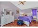 Bright bedroom with wood floors, dresser with mirror, bed with purple comforter and ceiling fan at 1906 Chathamoor Dr, Orlando, FL 32835