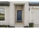Inviting front entryway with a stylish blue door, contemporary lighting, and manicured landscaping at 1940 Piedmont Ct, Mascotte, FL 34753