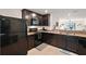 Modern kitchen with dark cabinets, granite countertops, and stainless steel appliances open to the living area at 1940 Piedmont Ct, Mascotte, FL 34753