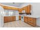Functional kitchen with light wood cabinetry, white appliances, and tile backsplash and floors at 204 Lori Ct, Umatilla, FL 32784