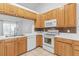 Close up of the kitchen with wooden cabinetry, tiled countertops and a white microwave and oven at 204 Lori Ct, Umatilla, FL 32784