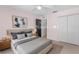 Staged main bedroom with artwork, nightstands and grey bed with many pillows at 204 Lori Ct, Umatilla, FL 32784
