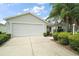 Front exterior featuring a two-car garage, landscaping, and a well-kept lawn, enhancing curb appeal at 2207 Crawford Ct, The Villages, FL 32162