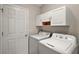 A practical laundry room featuring a washer, dryer, cabinets, and door for convenience at 2207 Crawford Ct, The Villages, FL 32162