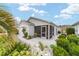 Back exterior featuring an enclosed patio with small bushes, palms, and well maintained grass at 2237 Jetta Way, The Villages, FL 32162