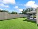 Expansive backyard with a privacy wall, lush green grass, and a screened porch at 2369 Five Forks Trl, The Villages, FL 32162