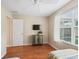 Bedroom with hardwood floors, window, television, ceiling fan, and small cabinet at 2369 Five Forks Trl, The Villages, FL 32162