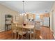 A well-lit dining room showcasing wooden floors, elegant lighting, and seamless integration with the kitchen's functional design at 2369 Five Forks Trl, The Villages, FL 32162
