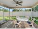 Screened porch with a round table and four white wicker chairs provides an outdoor seating area at 2369 Five Forks Trl, The Villages, FL 32162