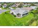 Drone shot of a white, single-story home with a screened lanai and immaculate lawn at 2455 Five Forks Trl, The Villages, FL 32162