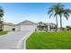 Charming single-story home featuring a well-manicured lawn, palm trees, and an attached garage at 2455 Five Forks Trl, The Villages, FL 32162