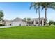 Well-maintained single-story home with lush green lawn, palm trees, and a welcoming entrance at 2455 Five Forks Trl, The Villages, FL 32162