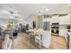 Open kitchen features white cabinets, stainless steel appliances, an island with seating, and an open floorplan to living area at 2455 Five Forks Trl, The Villages, FL 32162