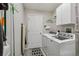 Functional laundry room with modern appliances, storage cabinets, and an ironing board at 2455 Five Forks Trl, The Villages, FL 32162