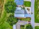 An aerial view shows a home with a well-maintained lawn, mature trees, and a driveway with multiple parked cars at 25007 Bellevue, Leesburg, FL 34748
