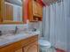 This bathroom features a vanity with granite countertop, a mirror, cabinet, and a shower behind a curtain at 25007 Bellevue, Leesburg, FL 34748