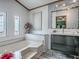 Bright bathroom with white tiled walls, a deep soaking tub, and stylish vanity with a modern mirror at 25007 Bellevue, Leesburg, FL 34748