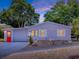 Charming home exterior with garage and red front door, surrounded by neatly maintained landscaping and colorful plants at 25007 Bellevue, Leesburg, FL 34748
