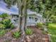 Charming home exterior with white trim, inviting porch, mature trees, and landscaped front yard, creating a serene setting at 25007 Bellevue, Leesburg, FL 34748