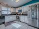 Functional kitchen featuring stainless steel refrigerator, white cabinets, granite countertops, and tiled floors at 25007 Bellevue, Leesburg, FL 34748