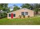 Charming one-story home featuring a red front door, well-maintained lawn, and mature trees at 256 Carroll St, Clermont, FL 34711