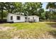 Backyard of white house features green grass and some areas of exposed dirt at 25824 Shawnee St, Sorrento, FL 32776