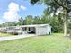 Bright white home with a covered carport and enclosed porch surrounded by a green lawn at 2585 Karen Dr, Mount Dora, FL 32757