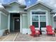 Inviting front porch area with two red chairs and attractive front door with windows and wreath at 2648 Maymont Ct, The Villages, FL 32163