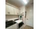 A well-lit laundry room featuring white cabinets above the washer and dryer at 2648 Maymont Ct, The Villages, FL 32163
