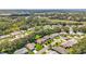 An aerial view displays a 55+ community surrounded by lush green trees, well manicured lawns, and a winding road at 27141 Racquet Cir, Leesburg, FL 34748