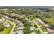 An aerial view of a 55+ community with well-maintained homes, lush greenery, and a serene pond at 27141 Racquet Cir, Leesburg, FL 34748