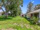 Expansive backyard with lush green lawn, mature trees, and the home's exterior at 27141 Racquet Cir, Leesburg, FL 34748