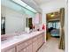 Bathroom with a double vanity, pink countertops, and a large mirror at 27141 Racquet Cir, Leesburg, FL 34748