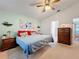 Well-lit bedroom features a ceiling fan, blue comforter, and classic wooden nightstands at 27141 Racquet Cir, Leesburg, FL 34748