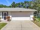 Attached two-car garage with a concrete driveway and manicured landscaping surrounding the entrance at 27141 Racquet Cir, Leesburg, FL 34748