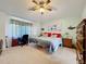 A cozy main bedroom featuring a ceiling fan, a large window, neutral walls, and matching nightstands at 27141 Racquet Cir, Leesburg, FL 34748