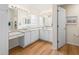 Bright bathroom featuring dual sinks, white cabinets, and hardwood floors at 3057 Saint Thomas Ln, The Villages, FL 32162