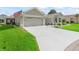 View of the home's gray concrete driveway, attached two-car garage, tidy front yard, and an American flag at 3057 Saint Thomas Ln, The Villages, FL 32162
