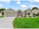 Beautiful home featuring a well-maintained lawn, gray concrete driveway, attached garage, and landscaped front yard at 3057 Saint Thomas Ln, The Villages, FL 32162