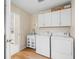 Bright laundry room with white cabinets, utility sink, modern washer and dryer, and wood-look flooring at 3057 Saint Thomas Ln, The Villages, FL 32162