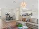 Bright living room featuring hardwood floors, an eat-in kitchen, and a comfortable grey sectional sofa at 3057 Saint Thomas Ln, The Villages, FL 32162