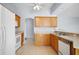 Well-lit kitchen featuring wood cabinets, white appliances, and tile flooring for easy maintenance at 33234 Kaylee Way, Leesburg, FL 34788