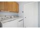 Practical laundry area with wooden cabinets and white washer/dryer for convenience at 33234 Kaylee Way, Leesburg, FL 34788