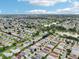 Vast aerial shot showcases a peaceful residential area with mature trees, winding roads, and a tranquil lake at 3460 Idlewood Loop, The Villages, FL 32162