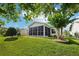 Serene backyard with a screened lanai, mature trees, and a well-maintained lawn, perfect for outdoor living at 3460 Idlewood Loop, The Villages, FL 32162