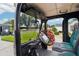 Comfortable golf cart interior with black and green seats and a view of the well-maintained neighborhood at 3460 Idlewood Loop, The Villages, FL 32162