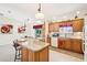 Well-lit kitchen featuring wooden cabinets, granite countertops, an island with barstools, and tile flooring at 3460 Idlewood Loop, The Villages, FL 32162