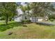 Spacious home with a lush green lawn, mature trees, and an attached two-car garage at 3604 Corsica Ln, Clermont, FL 34711
